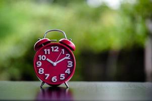 Black Antique Clock Red Metal Alarm Clock on Red Valentine's Day Love Concept Red clock on the table. photo
