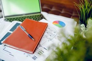 Business desk with business notebook, desk, pen, paper, table graph, top view with copy space photo
