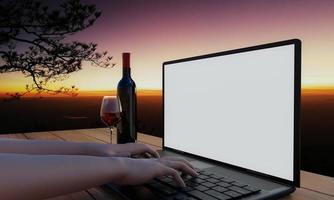 una computadora o computadora portátil con una pantalla en blanco sobre una mesa de madera con una copa de vino tinto y una botella. trabajar al aire libre para la recreación. paisajes de montaña con pinos y luz del sol por la mañana. representación 3d foto