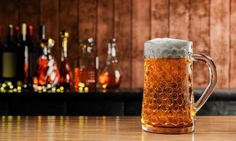 Draft or craft beer in tall clear glass. With cold steam, White beer foam placed on a wooden floor, behind the background is a bottle of wine, whiskey, brandy at the restaurant or bar. 3D Rendering photo