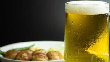 Beer in a glass, slightly foaming. and water droplets cling to the glass. A cold alcoholic drink with a background as an appetizer is sausage. photo