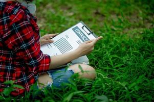 Hand of staff, marketing manager pointing to business documents and sitting under the tree - Business ideas photo