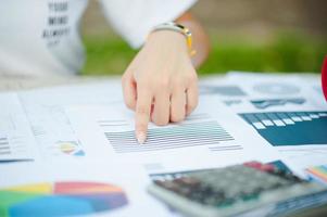 Woman sitting at desk and working at hand of book and financial documents close up photo