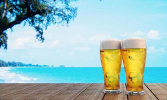 Draft or craft beer in a tall clear glass With beer foam on top And there are bubbles in the glass. Cold beer in a glass, placed on a wooden table on the beach, the sea during the day. 3D Rendering