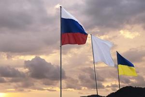 Ukraine and Russia official national flag on blue sky background at sunset. photo