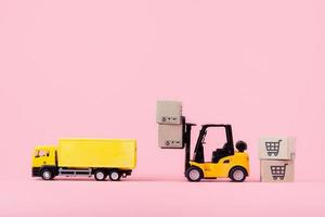 Logistics, and delivery service - Cargo truck, Forklift and paper cartons or parcel with a shopping cart logo on Pink background. Shopping service on The online web and offers home delivery. photo