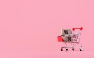 Shopping concept. Cartons or Paper boxes in red shopping cart on pink background. online shopping consumers can shop from home and delivery service. with copy space photo