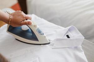 Hand ironing white shirt on ironing board photo
