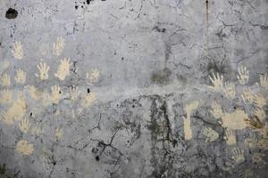 Cracked gray wall background texture with hand print photo