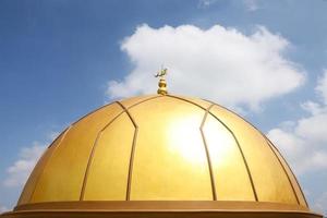cúpula dorada y torre alta de la mezquita con fondo de cielo foto