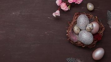 Flat lay Easter nest and eggs on brown bakcground with pink blossom flowers copy space photo