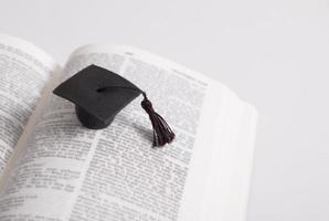 gorra de posgrado en las páginas de la santa biblia. concepto de educación espiritual foto