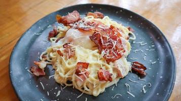 Carbonara spaghetti with onsen egg, crispy bacon, hard parmesan cheese and cream sauce. photo