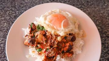 Sunny side up egg top on spicy stir fried beef and basil with steamed rice. photo