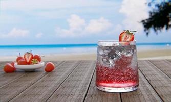 el néctar de fresas sin alcohol con soda no mezcla alcohol. las fresas frescas en una taza de cerámica están en el desenfoque de fondo colocadas en una mesa de madera. el restaurante en la playa y el mar .3d renderizado foto