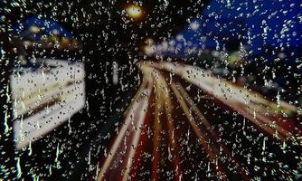 agua de lluvia en el vaso en un día lluvioso. gotas de agua en el cristal de la ventana. con imágenes de fondo para el tráfico en la carretera nocturna, hay una luz de camión en la carretera. representación 3d foto