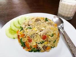 One kind of Thai breakfast Pork Fried Rice with Chicken Eggs With a mixture of carrots, kale, and tomatoes, decorating the edges of the dish by cucumbers On a white circular plate photo