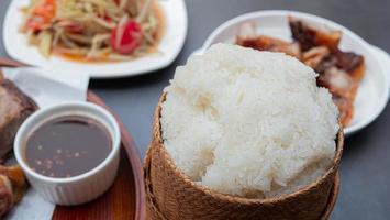 tibio arroz pegajoso al vapor, poner en una cacerola. Recipiente de bambú para contener arroz glutinoso cocido. un alimento básico popular en el noreste de Tailandia. foto