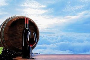 Red wine in clear glass and dark wine bottle Oak wine fermentation tank Placed on the floor of a wooden table There is a background in the morning mist.3D Rendering photo