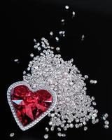 A red diamond or a large ruby in the shape of a heart, a symbol of love or Valentine's Day. A red diamond is placed on a pile of small diamonds. On the black reflection. 3D Rendering. photo