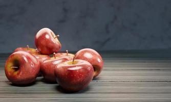 Fresh red apples are placed on a wooden table surface with a marble-patterned wall. 3D Rendering photo