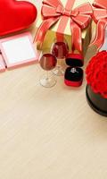 Celebrating love propose a diamond ring and a large bouquet of red diamonds Luxury gift box Red wine in Glass A blank photo frame. Blank white tablet screen is placed on Wood-grain table. 3D Rendering