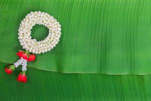 Songkran Festival background with jasmine garland on green banana leaf background photo