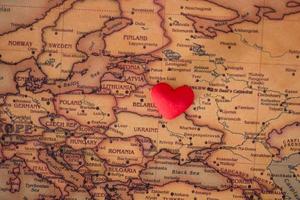 heart with national flag of ukraine on a vintage world map crack paper background. photo