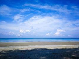 The bright blue sky and the bright white clouds, the beach and the clear blue sea in the daytime photo