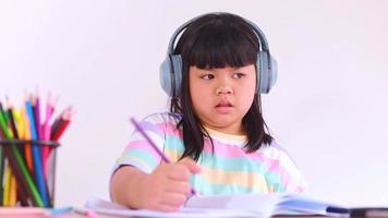 asiatische Studentin mit Kopfhörern, die von zu Hause aus online lernt