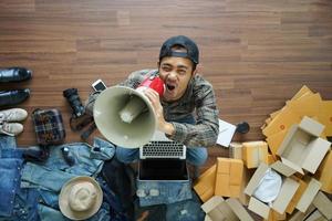 Top view of man holding megaphone advertising message marketing with fashion accessories on wooden floor from home. With postal parcel, Selling online ideas concept design photo