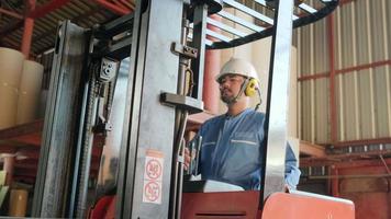 säkerhetsuniform manlig asiatisk industriarbetare och hjälm använder hydraulisk gaffeltruck, frakt och logistisk transport på lagertillverkning fabrik, leverans lager yrkesförare yrke. video