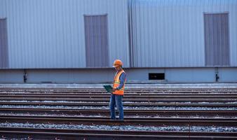 Engineer railway under  checking construction process train testing and checking railway work on railroad station with radio communication .Engineer wearing safety uniform and safety helmet in work. photo