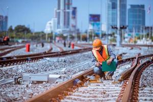 ingeniero ferroviario bajo control del proceso de construcción prueba de trenes y control del trabajo ferroviario en la estación de ferrocarril con comunicación por radio. ingeniero con uniforme de seguridad y casco de seguridad en el trabajo. foto