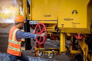 ingeniero ferroviario bajo control del proceso de construcción prueba de trenes y control del trabajo ferroviario en la estación de ferrocarril con comunicación por radio. ingeniero con uniforme de seguridad y casco de seguridad en el trabajo. foto