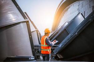 Industry engineer under checking the industry cooling tower air conditioner is water cooling tower air chiller HVAC of large industrial building to control air system. photo