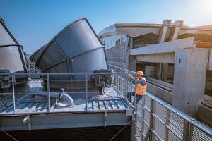 Industry engineer under checking the industry cooling tower air conditioner is water cooling tower air chiller HVAC of large industrial building to control air system. photo