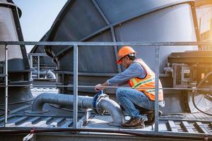 Industry engineer under checking the industry cooling tower air conditioner is water cooling tower air chiller HVAC of large industrial building to control air system. photo