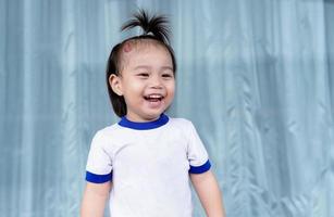 Close up of Adorable little child girl with large capillary strawberry hemangiomas red birthmark on head. Happy smiling girl, a positive female kid, looking at mother or someone. Health care concept photo