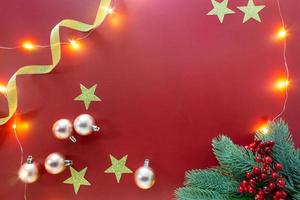Christmas background, gold ribbon, glitter stars, ornaments and branch leaves on red background for festive decoration. photo
