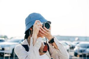 Attractive young adult asian woman traveller using camera for photo journey.