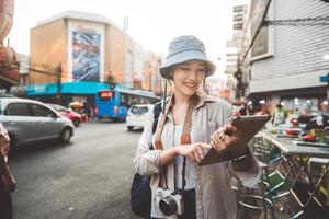 Young adult asian woman traveller solo traveling with modern teachnology using tablet. photo