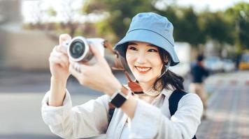 Attractive young adult asian woman traveller using camera for photo journey.
