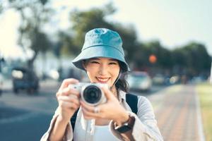 atractiva joven viajera asiática adulta usando cámara para un viaje fotográfico. foto