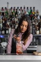Professional female mixologist preparing cocktail in bar photo