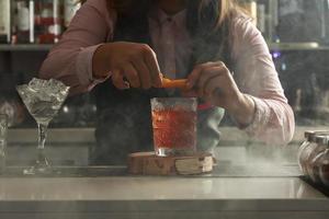 Bartender garnishing cocktail with orange peel photo