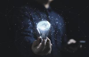 mano de hombre de negocios sosteniendo una bombilla con un cerebro virtual brillante y una línea de conexión con el pensamiento inteligente creativo para la inspiración y la innovación con el concepto de red. foto