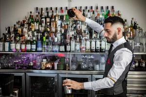 barman experto con agitador preparando un cóctel foto