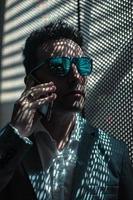 Respectable businessman in sunglasses talking on smartphone photo