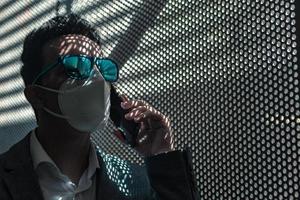 Businessman in protective mask talking on smartphone photo
